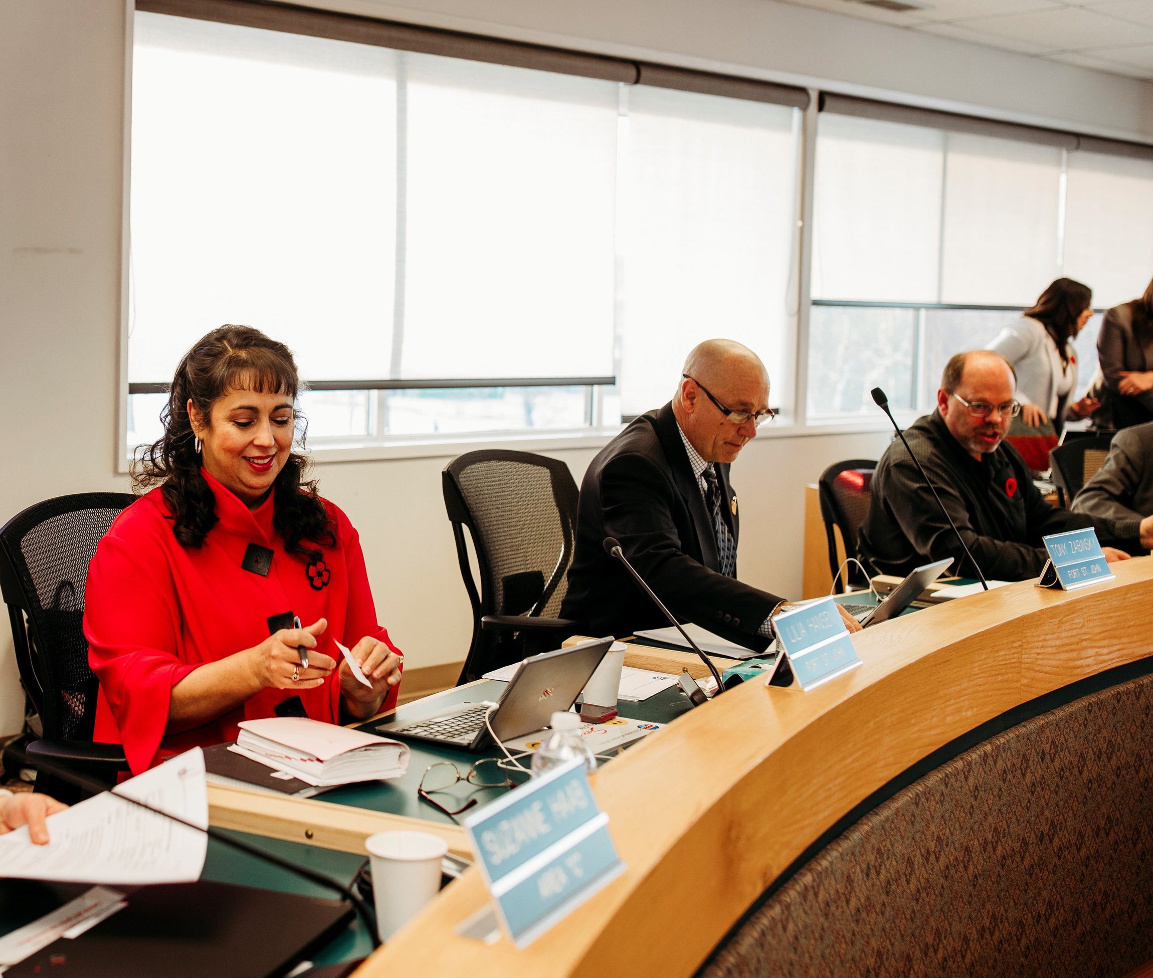 A group of people seated around a board room with documents open